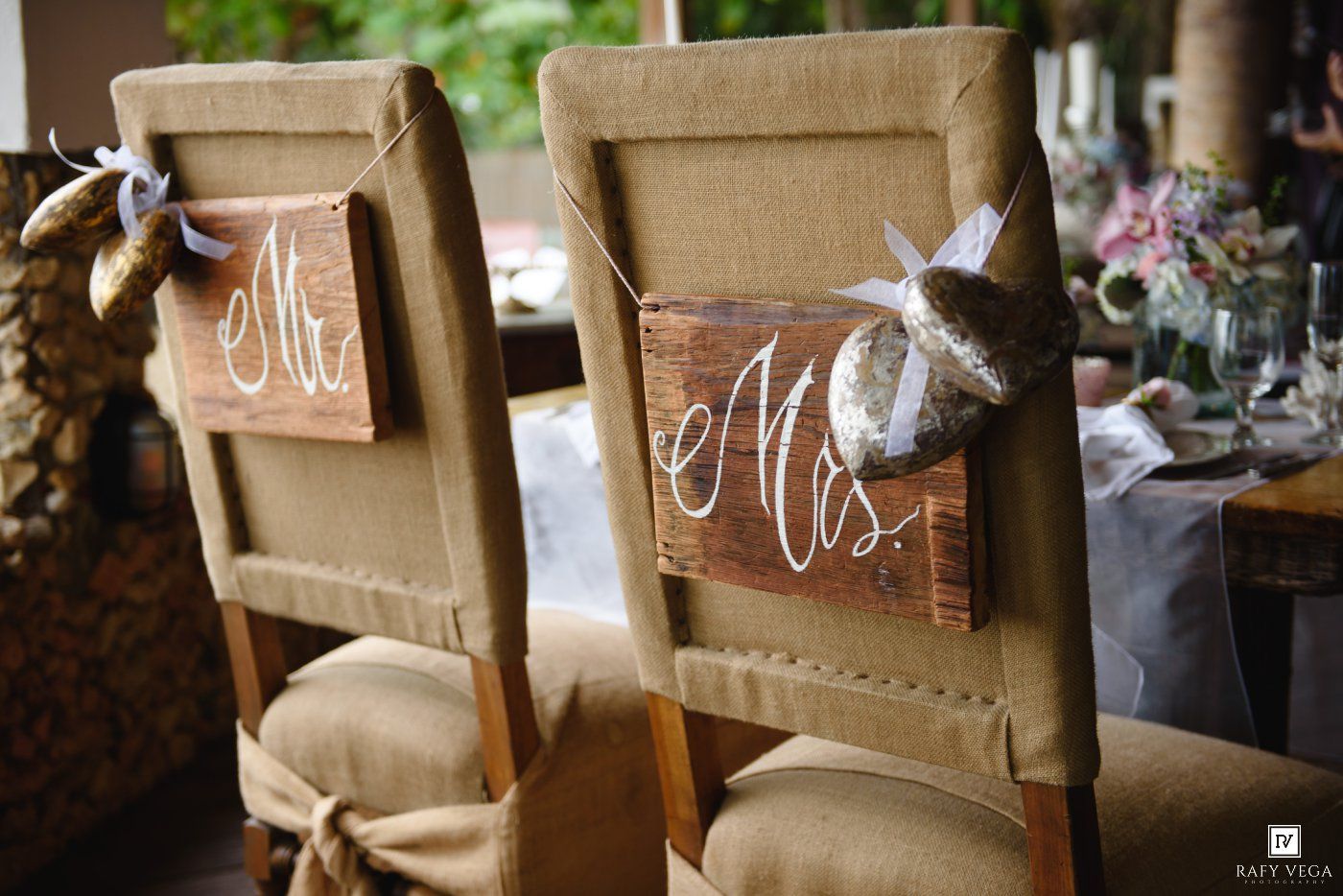 Rustic wooden Mr. and Mrs. signs hang on burlap-covered chairs at a wedding reception table.