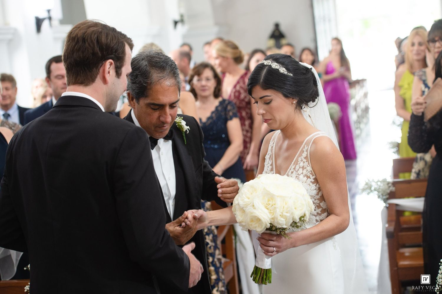 Bride and groom exchanging rings at wedding ceremony altar, bride holding white bouquet.