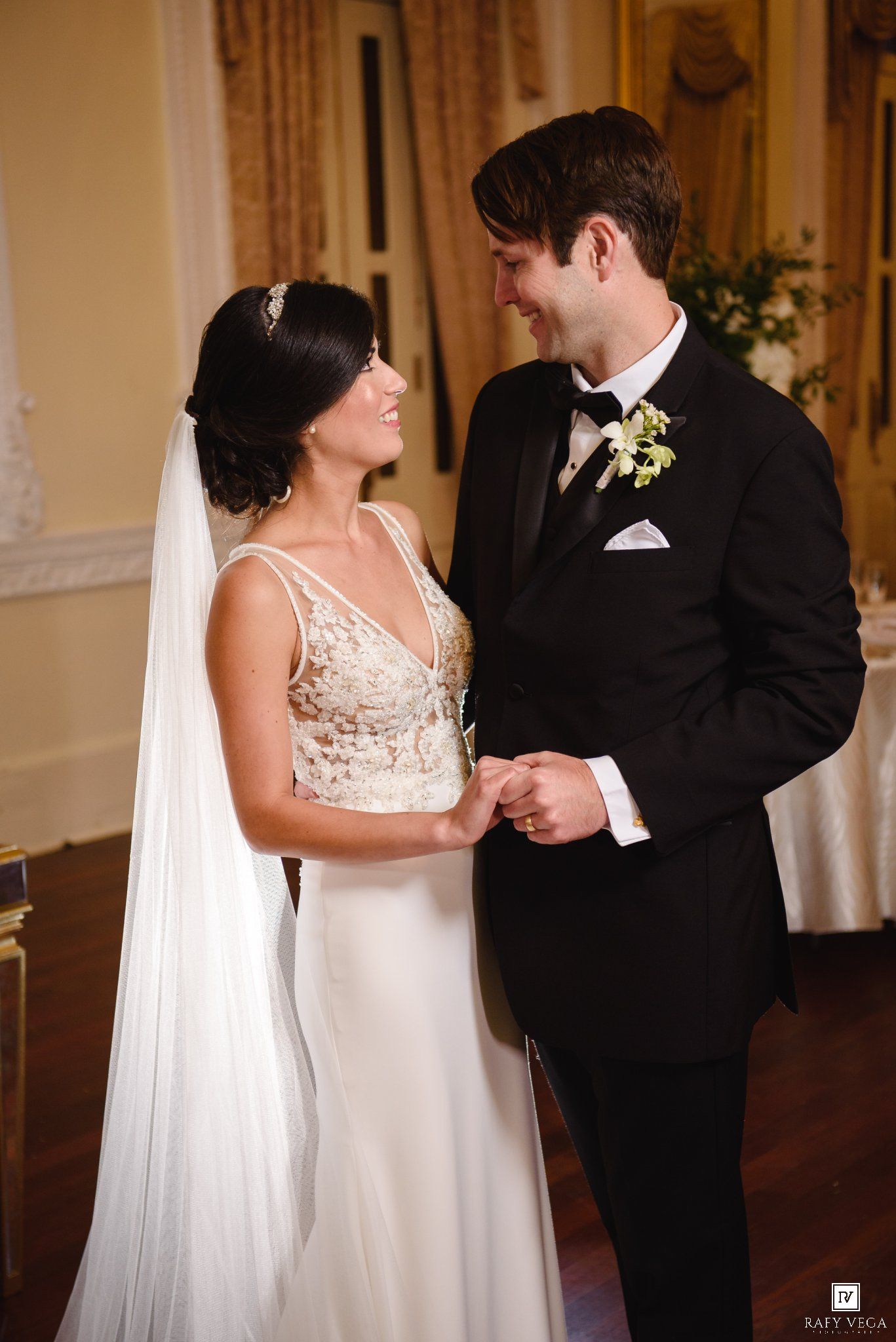 Bride and groom share a tender moment holding hands during their elegant wedding ceremony.