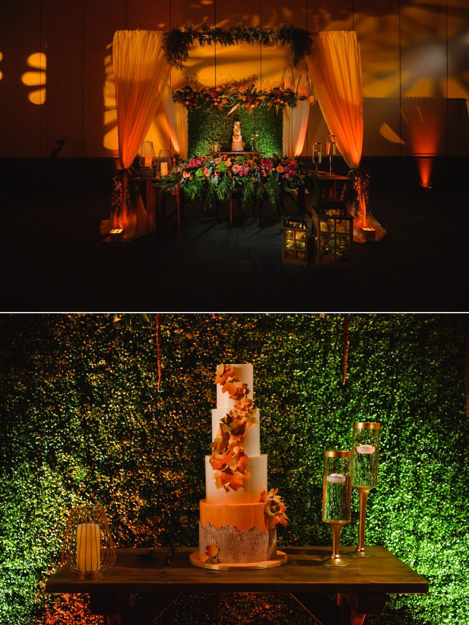 Elegant wedding reception with orange-lit floral backdrop, sweetheart table, and tiered cake display against lush green hedge wall.