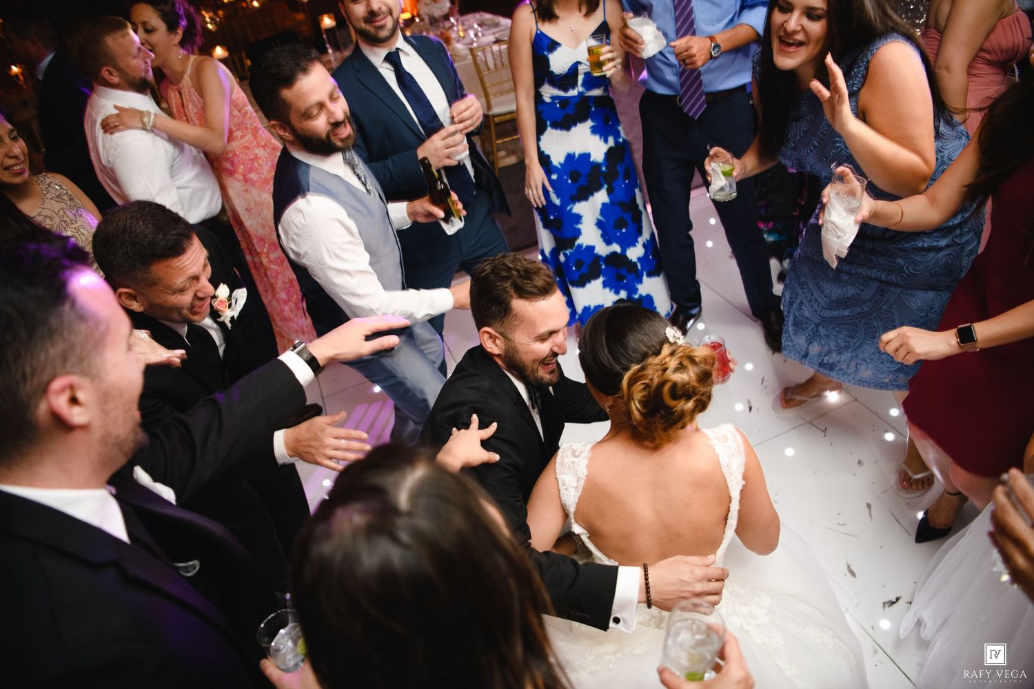 Wedding guests dancing and celebrating on a dance floor during a lively wedding reception party.