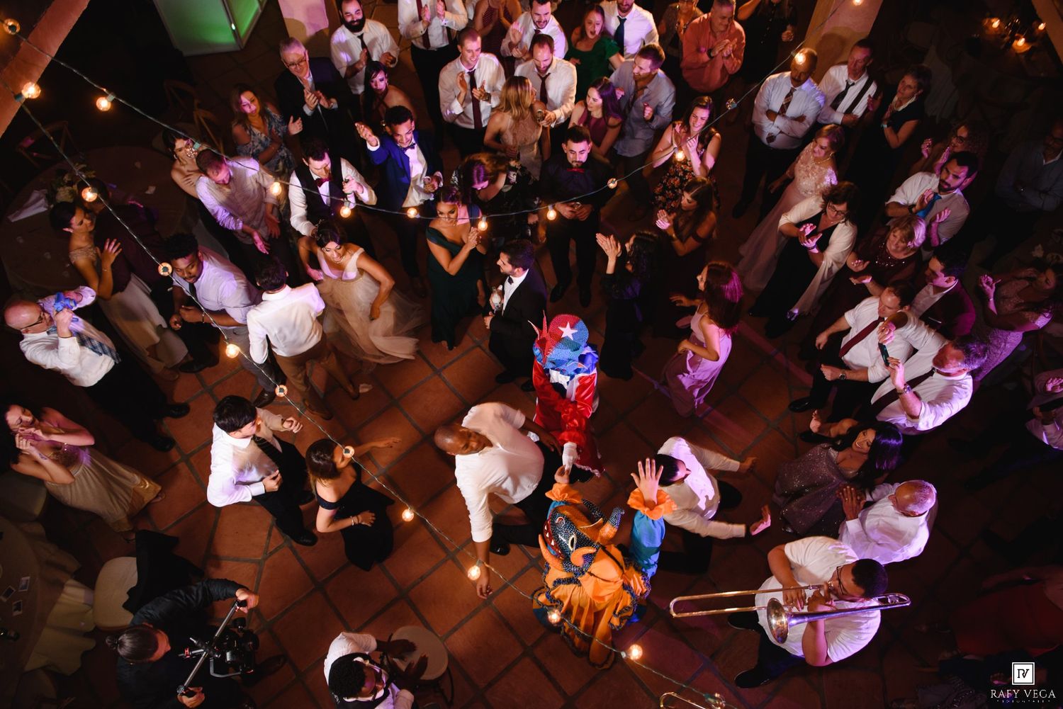 Aerial view of a lively wedding reception dance floor with guests dancing and a band performing.