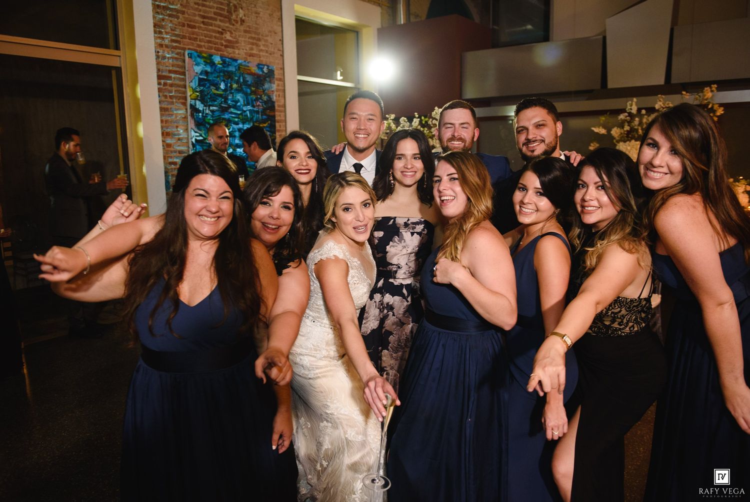 Bride poses with bridesmaids in navy blue dresses at elegant wedding reception venue.