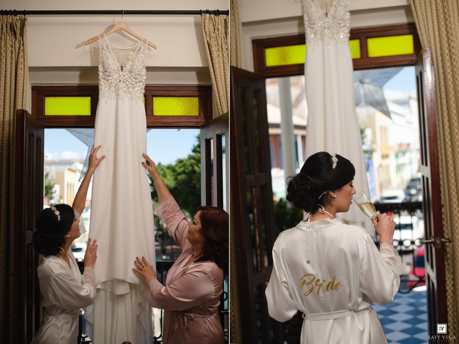 Bride in satin robe admires wedding dress hung by bridesmaids near bright window on wedding day.