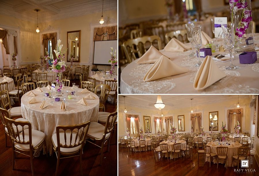 Elegant wedding reception hall with round tables, gold chairs, white linens, and purple floral centerpieces on hardwood floors.