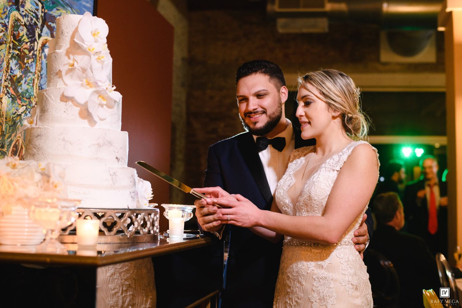 Bride and groom cutting their elegant white wedding cake together at their indoor wedding reception.