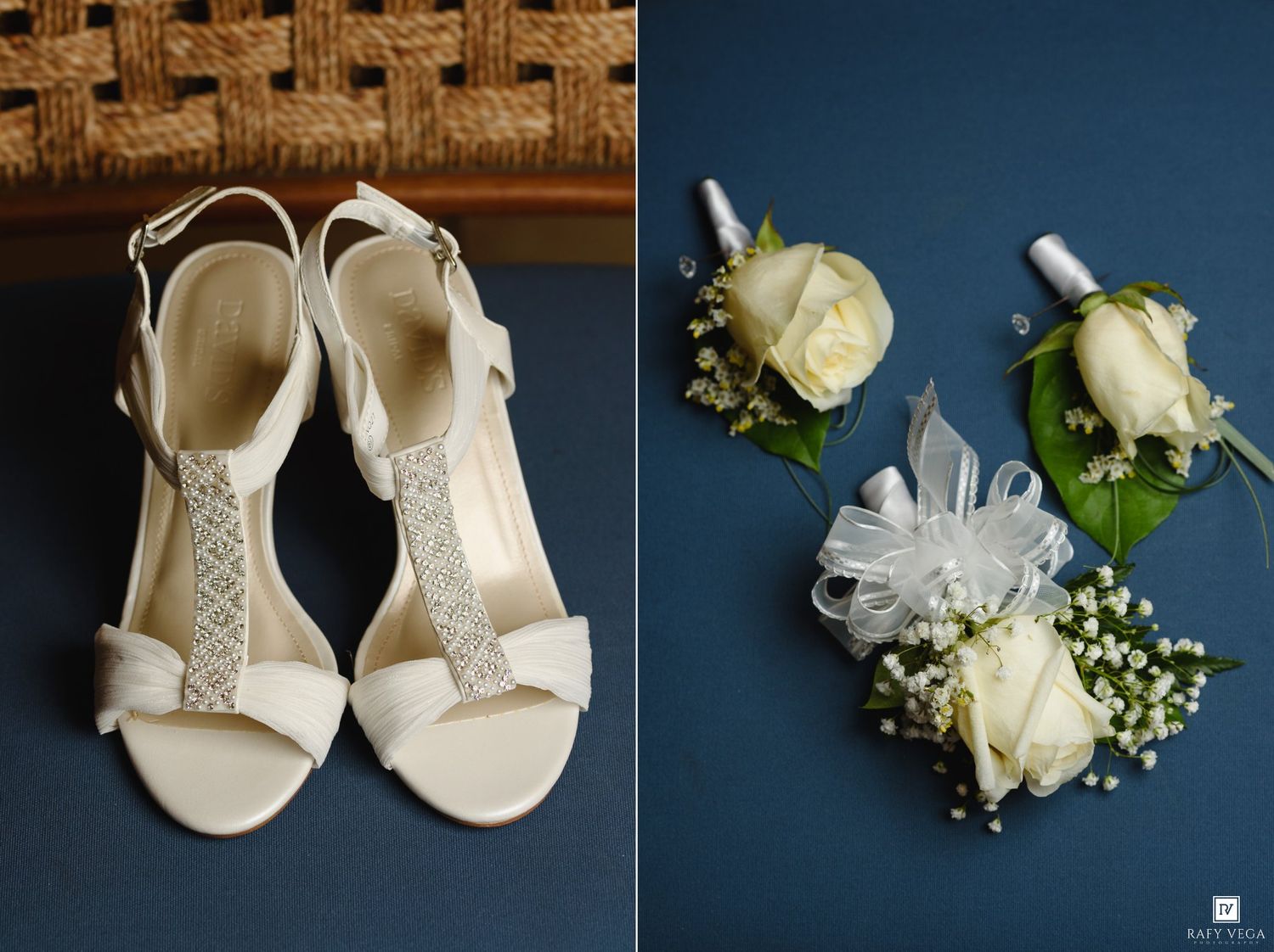 Elegant white bridal heeled sandals with crystal embellishment beside white rose boutonnieres with baby's breath on blue background.