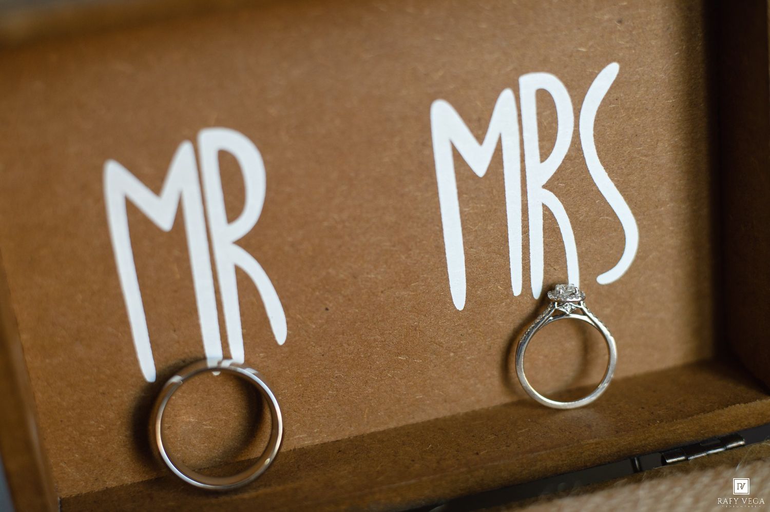 Wedding rings displayed in a wooden box with MR and MRS signs, symbolizing marriage and commitment.