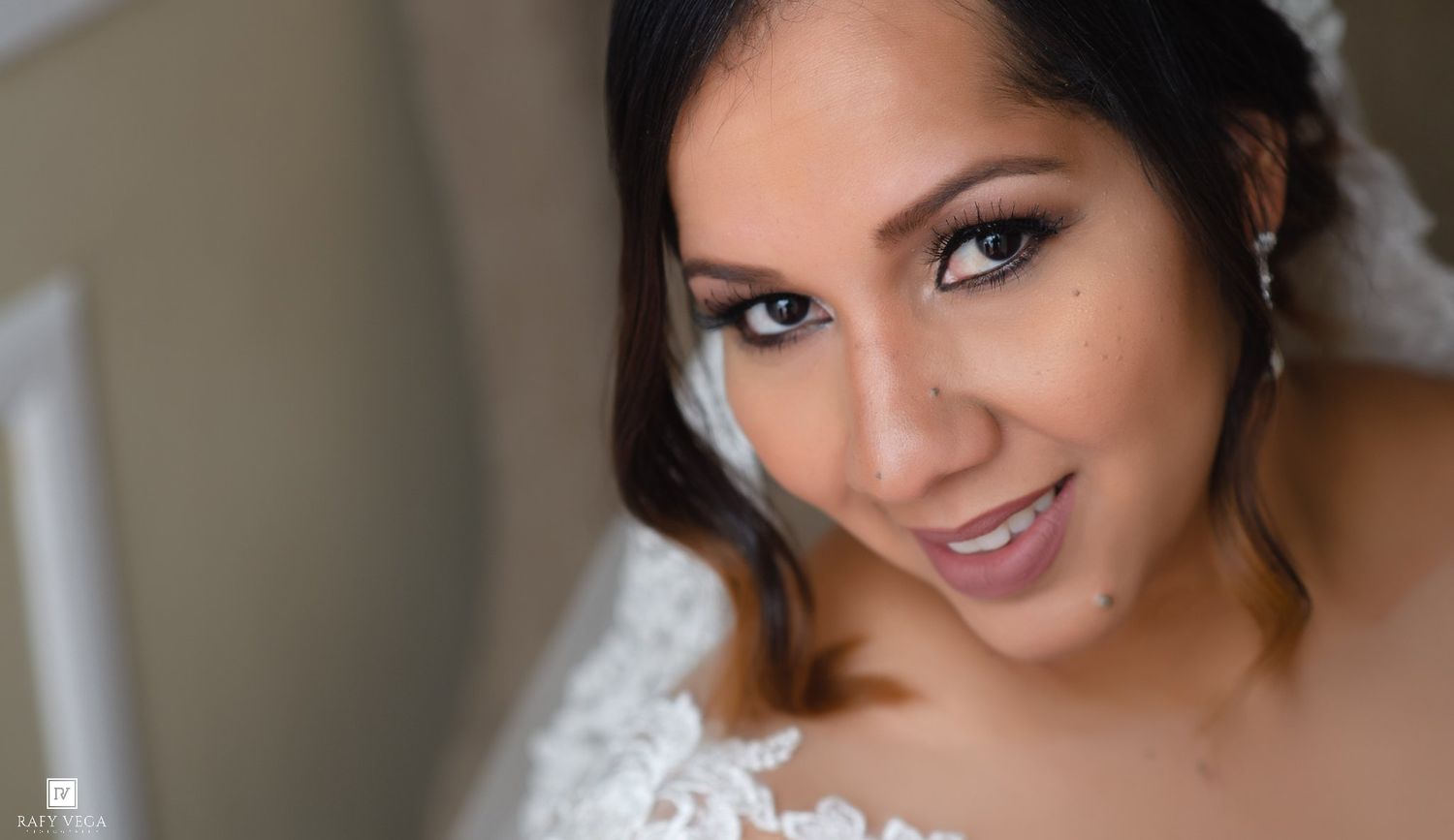 Close-up portrait of a beautiful bride in a white lace gown with elegant makeup and soft natural lighting.