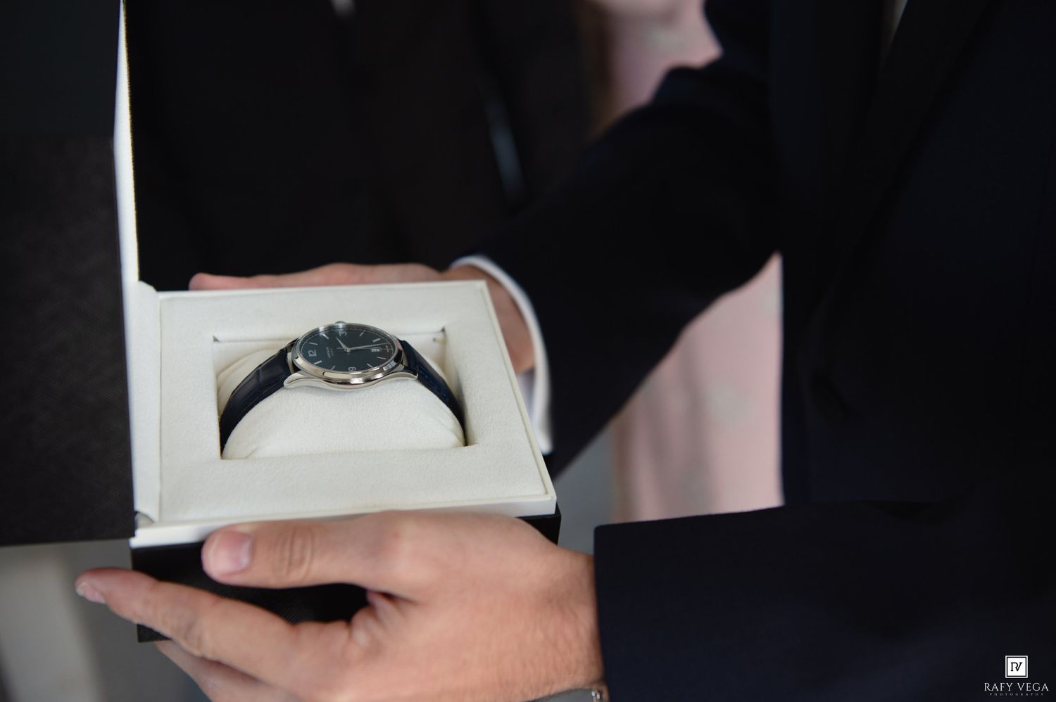 A luxury wristwatch with a dark dial and leather strap presented in an elegant white gift box.