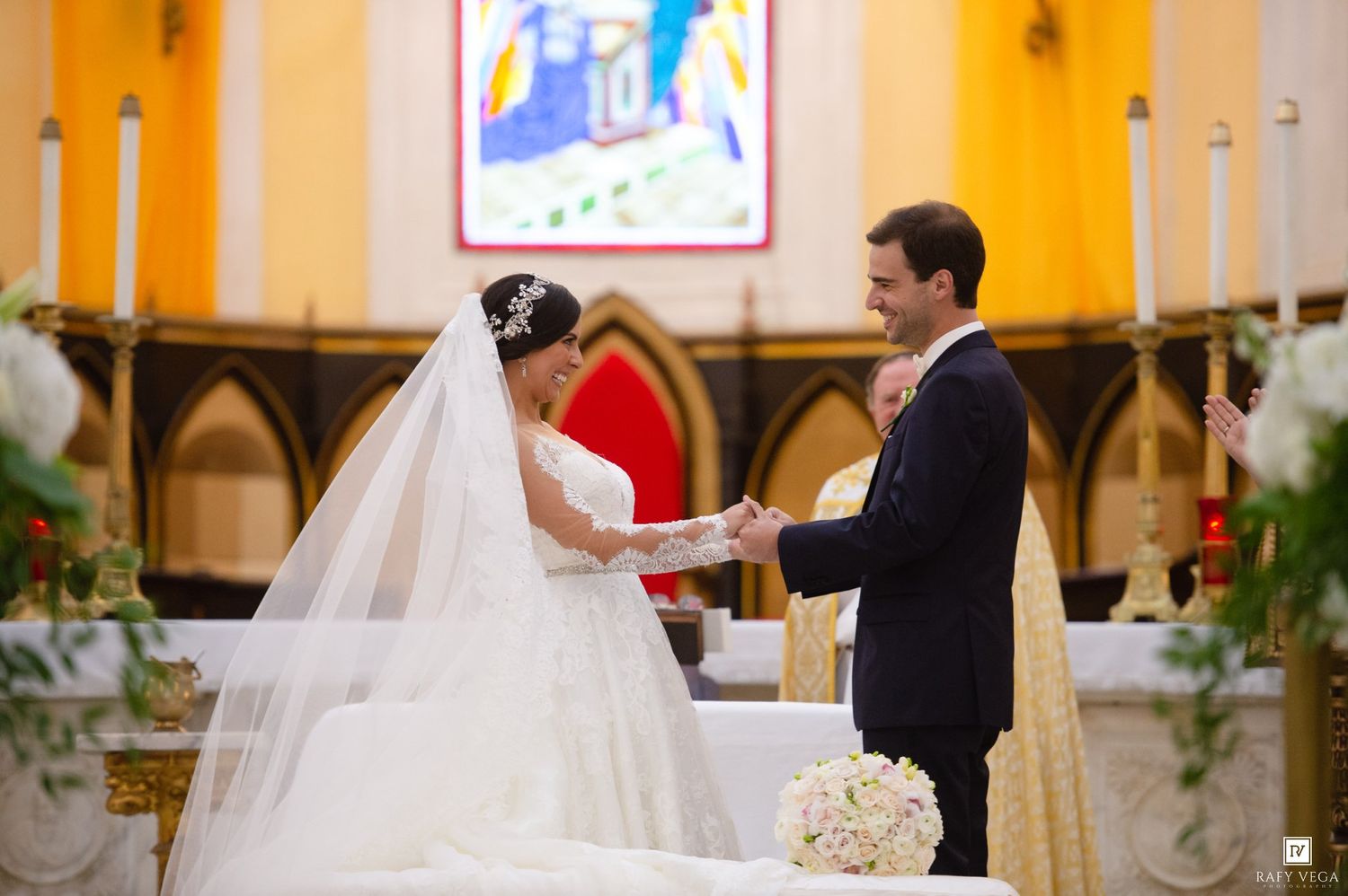Bride and groom exchange vows at a decorated church altar, bride in white gown with veil and tiara.