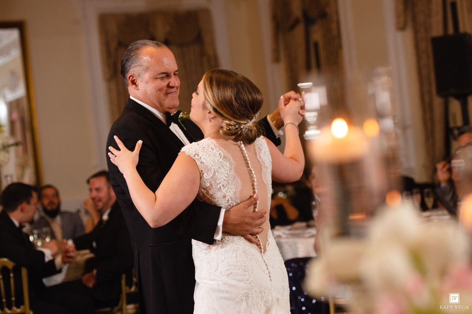 Bride and groom share a joyful dance together at their wedding reception with guests watching.