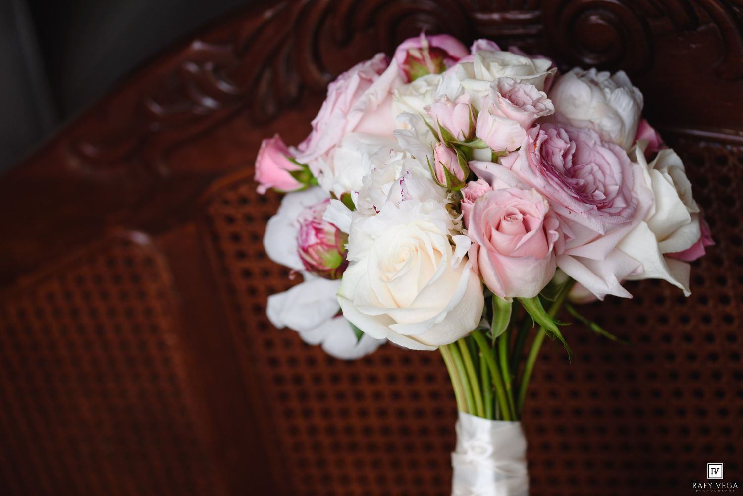 Elegant bridal bouquet of pink and white roses on a wooden chair.