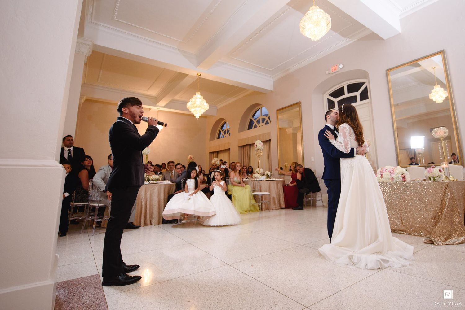 Bride and groom share first dance as a singer performs live at an elegant wedding reception venue.