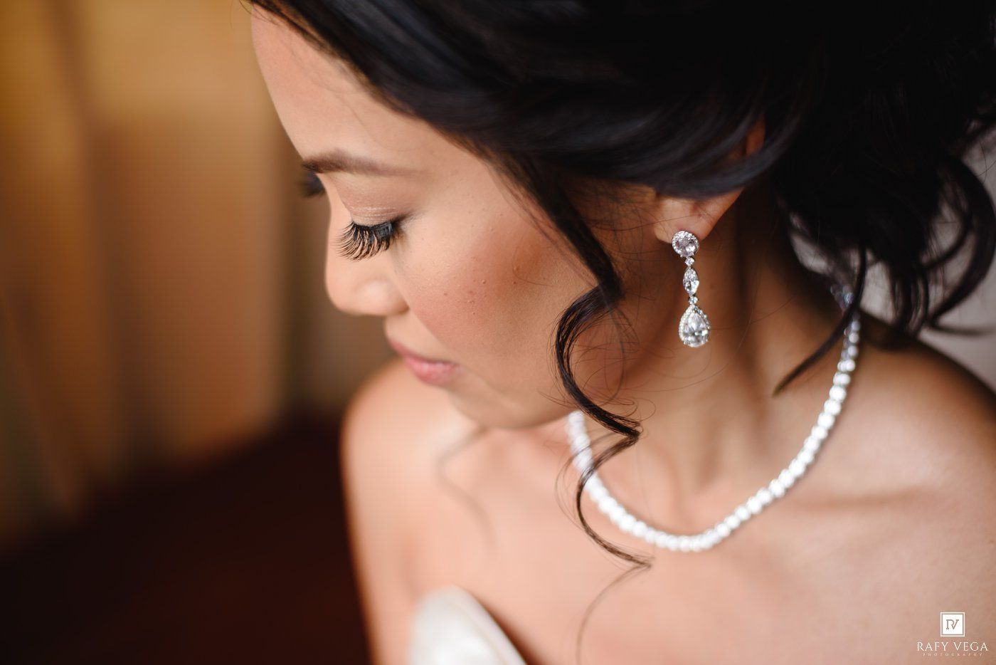 Close-up of a bride wearing pearl earrings and necklace with elegant updo hairstyle on her wedding day.