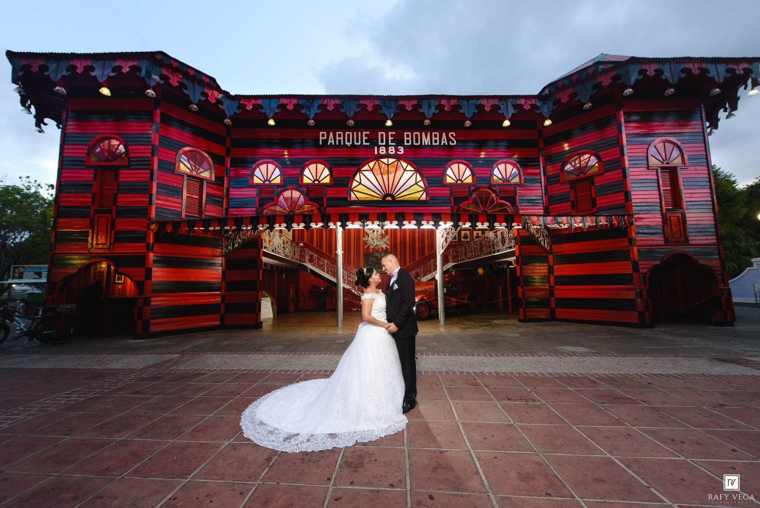 Newlyweds share a romantic kiss in front of the iconic red and black Parque de Bombas building in Ponce, Puerto Rico.
