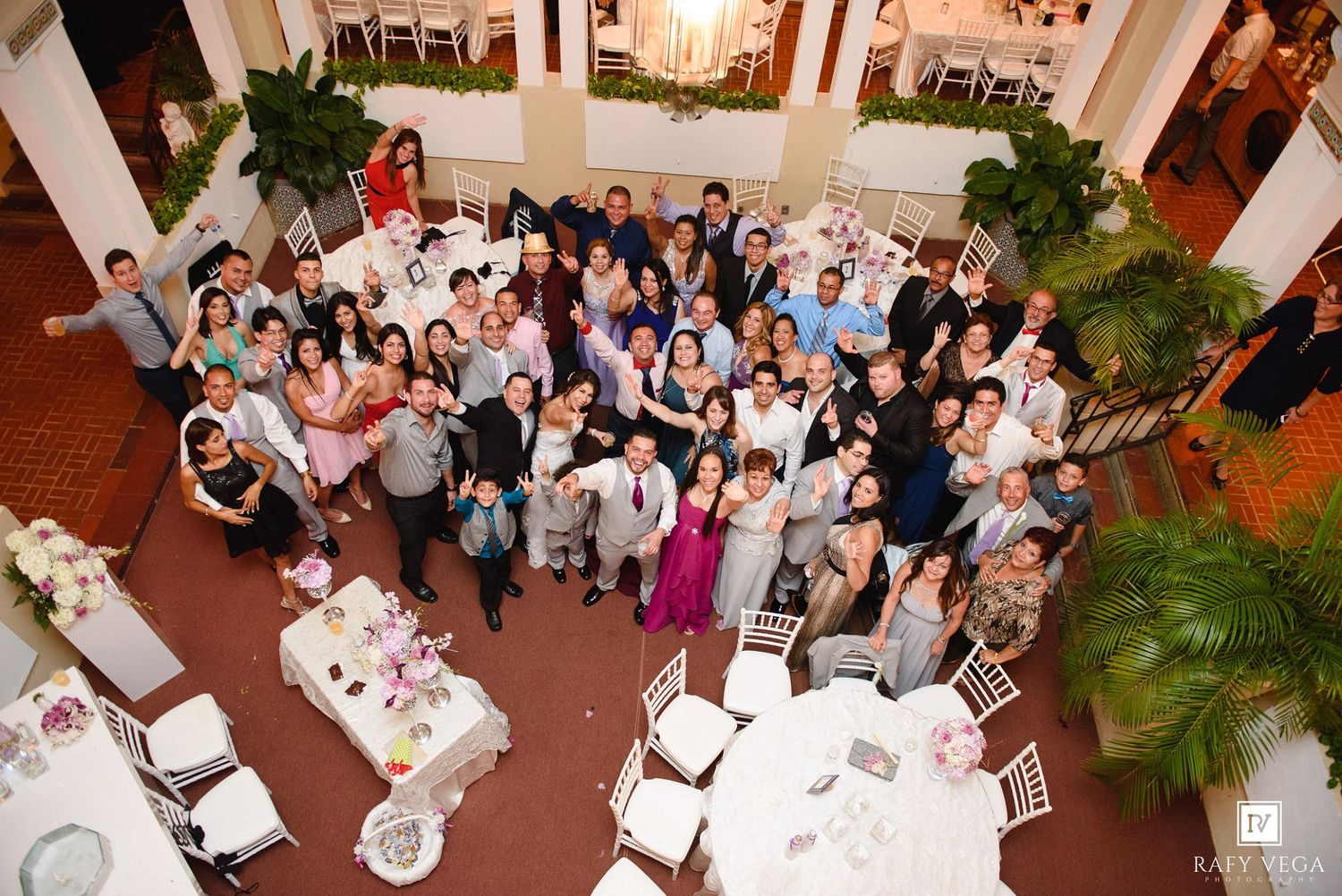 Large wedding reception group photo taken from above showing guests celebrating in elegant banquet hall.