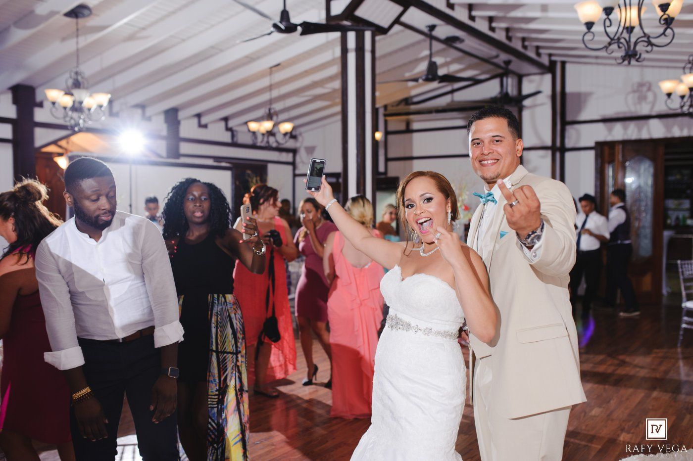 Bride and groom dancing joyfully with guests at elegant wedding reception venue.