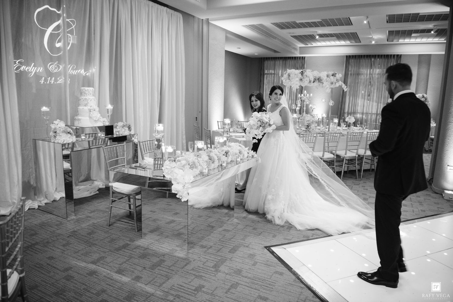 Bride in ball gown and groom share a moment in beautifully decorated black and white wedding reception venue.