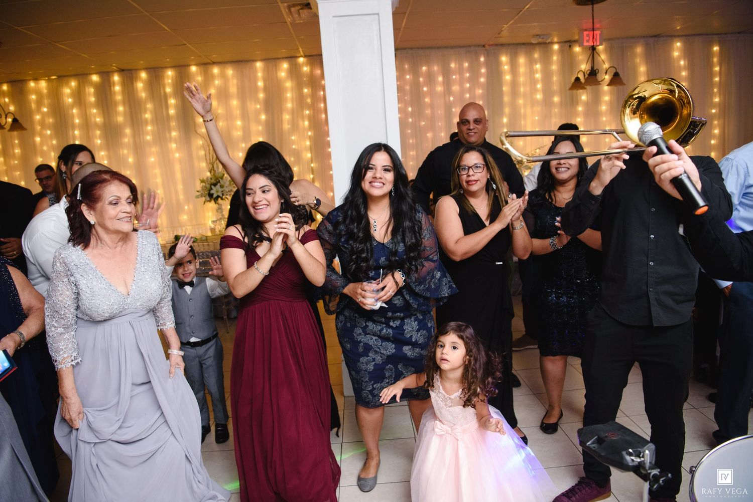 Guests dancing and celebrating at a wedding reception with live brass band music and fairy lights.