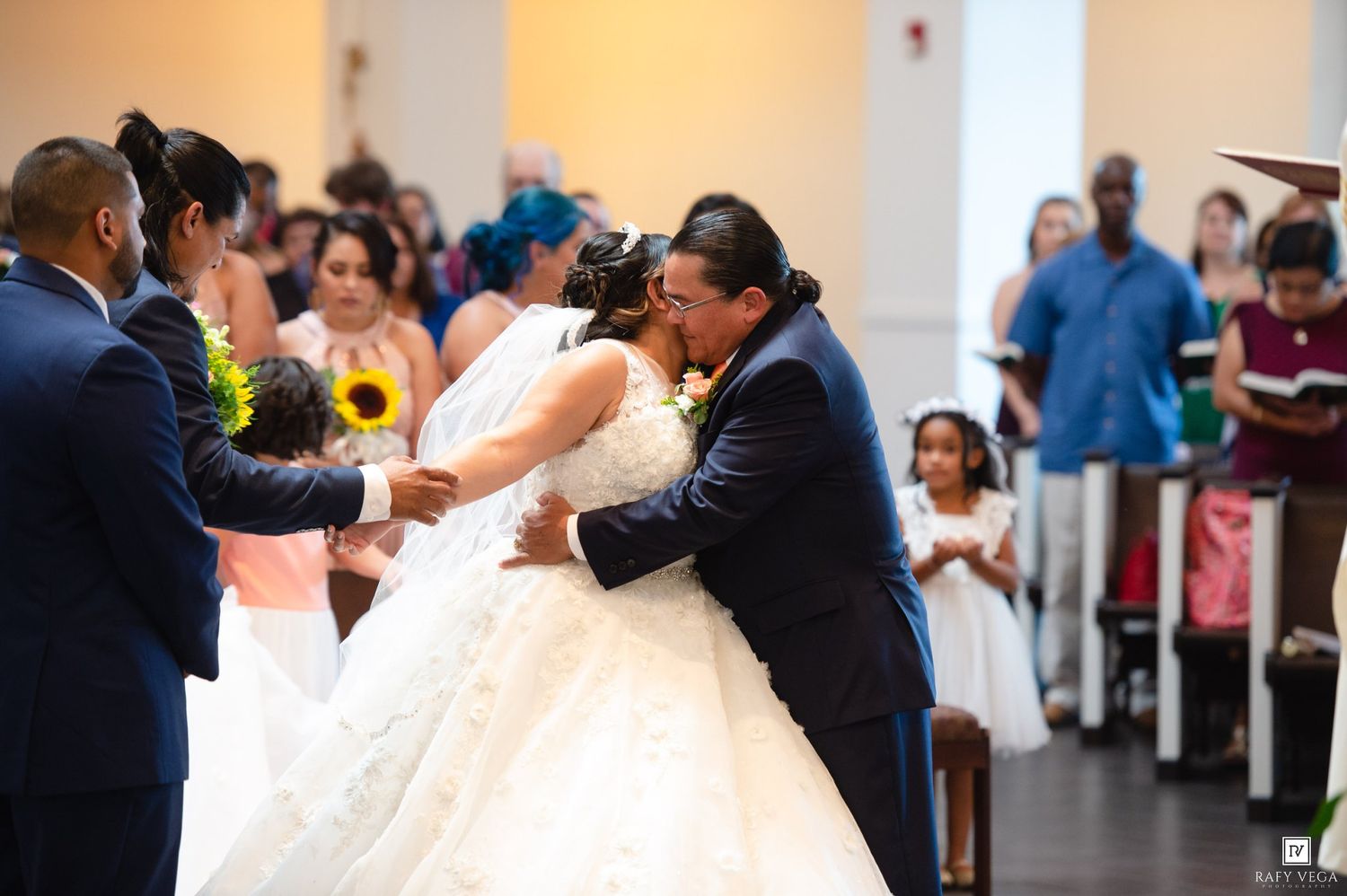 Bride and groom share their first kiss at the altar surrounded by wedding guests in a church.