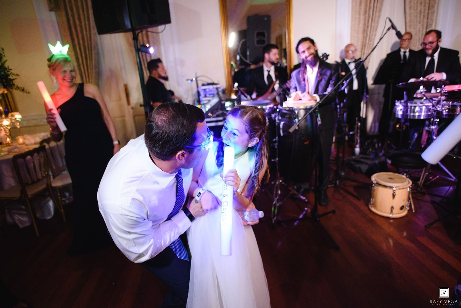 Bride and groom share their first dance at elegant wedding reception with live band performing in background.