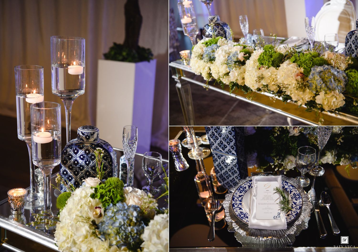 Elegant wedding table setting with tall glass candle holders, blue patterned china, white floral centerpieces, and gold accents.