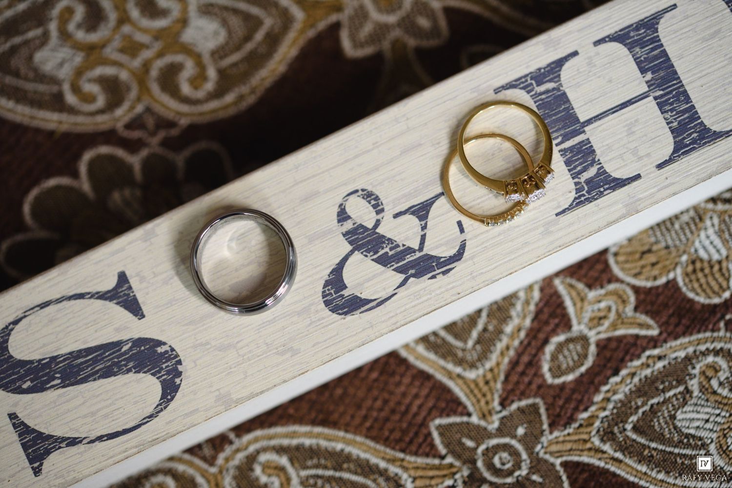 Two wedding rings rest on a wooden keepsake box engraved with initials S and H, symbolizing a couple's union.