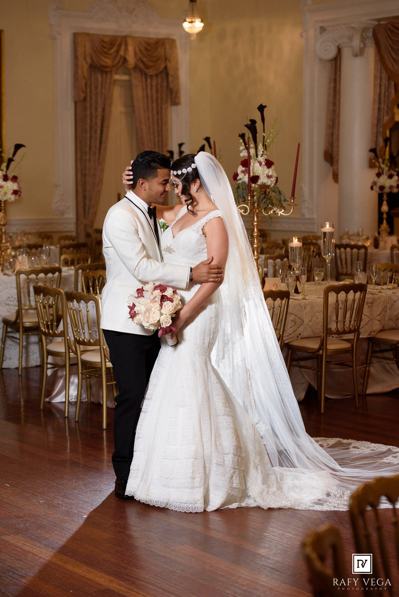 Bride and groom share a romantic moment on the dance floor in a beautifully decorated wedding reception hall.