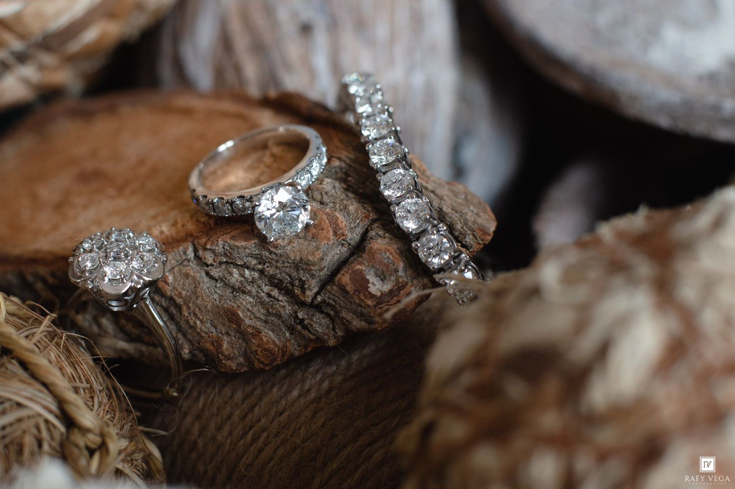 Three sparkling diamond rings displayed on rustic wooden bark, featuring a solitaire engagement ring and diamond band set.