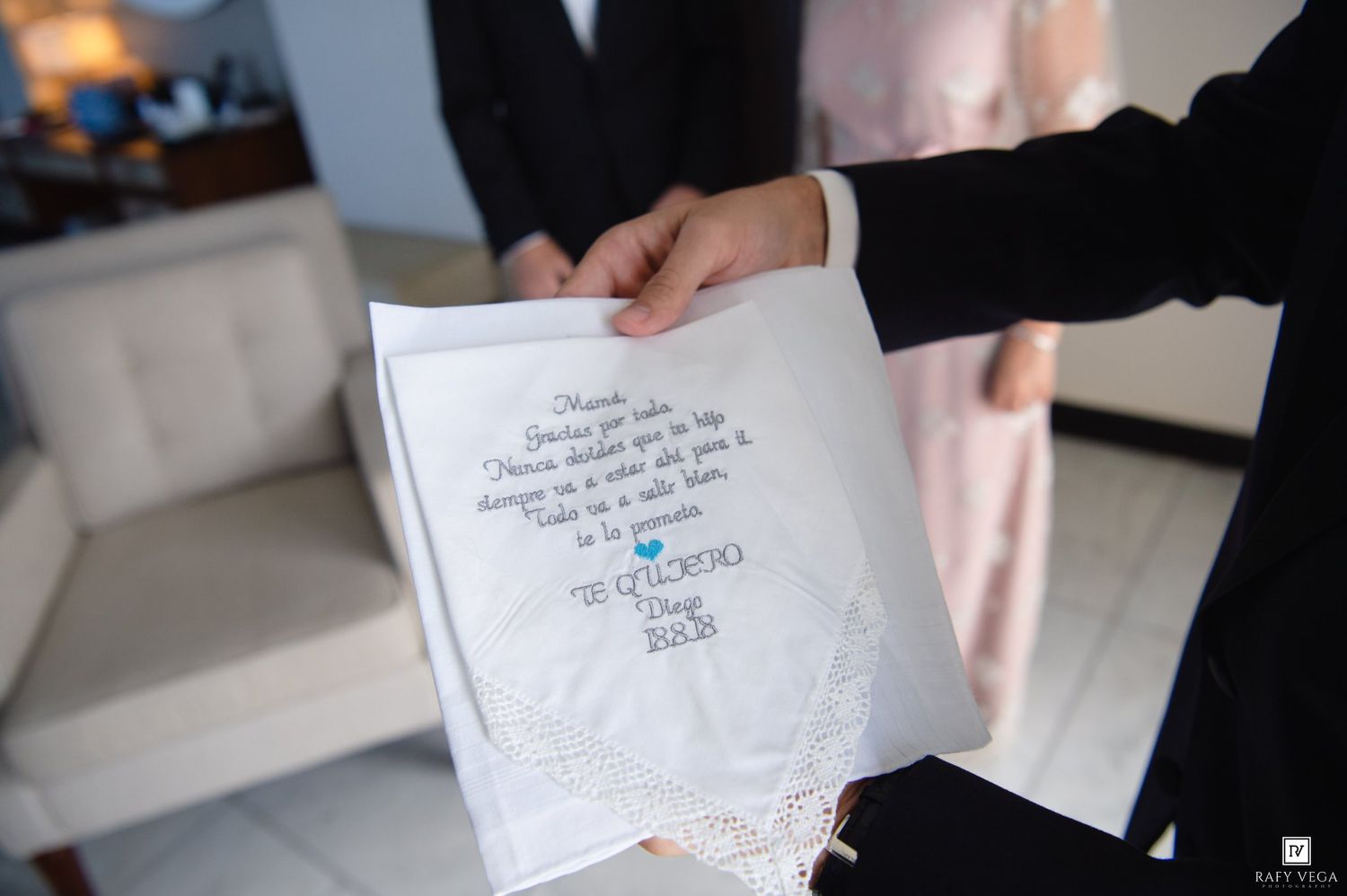 A personalized embroidered wedding handkerchief with a heartfelt message held by a groom.