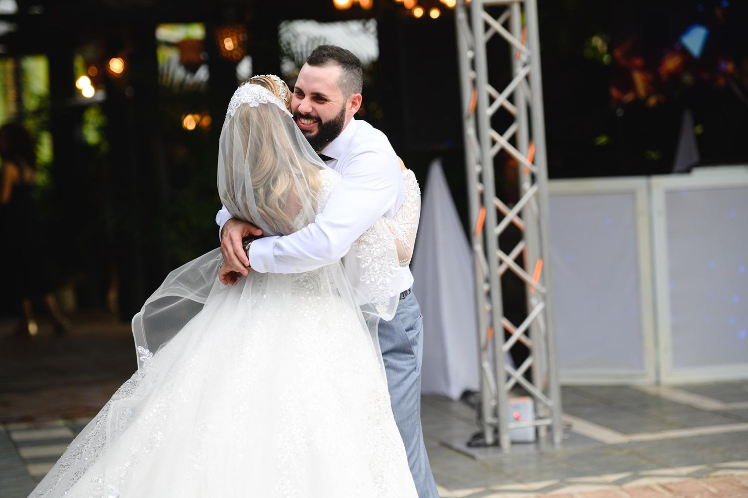 Bride and groom share their first dance, embracing warmly at an outdoor wedding reception.