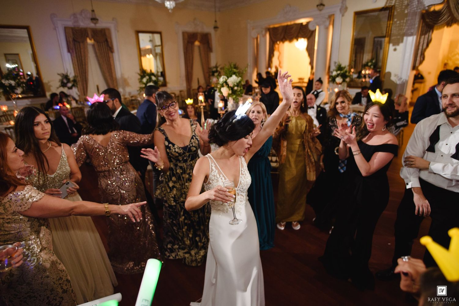 Bride in white gown dancing joyfully with guests at elegant wedding reception celebration.