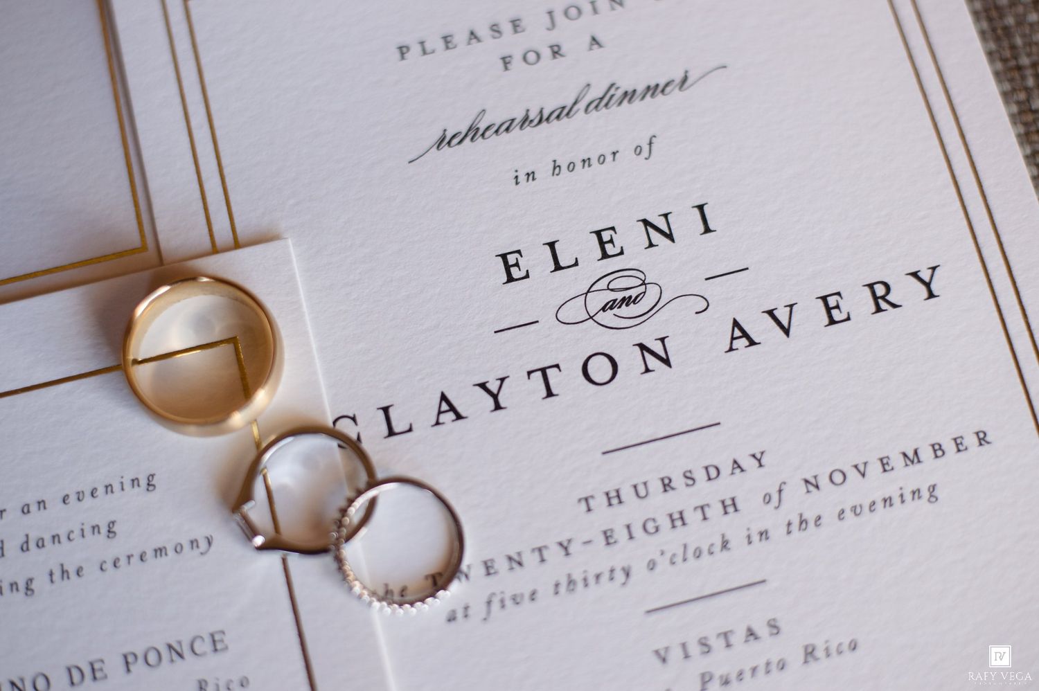 Gold wedding rings rest on elegant rehearsal dinner invitations for Eleni and Clayton Avery on a white background.