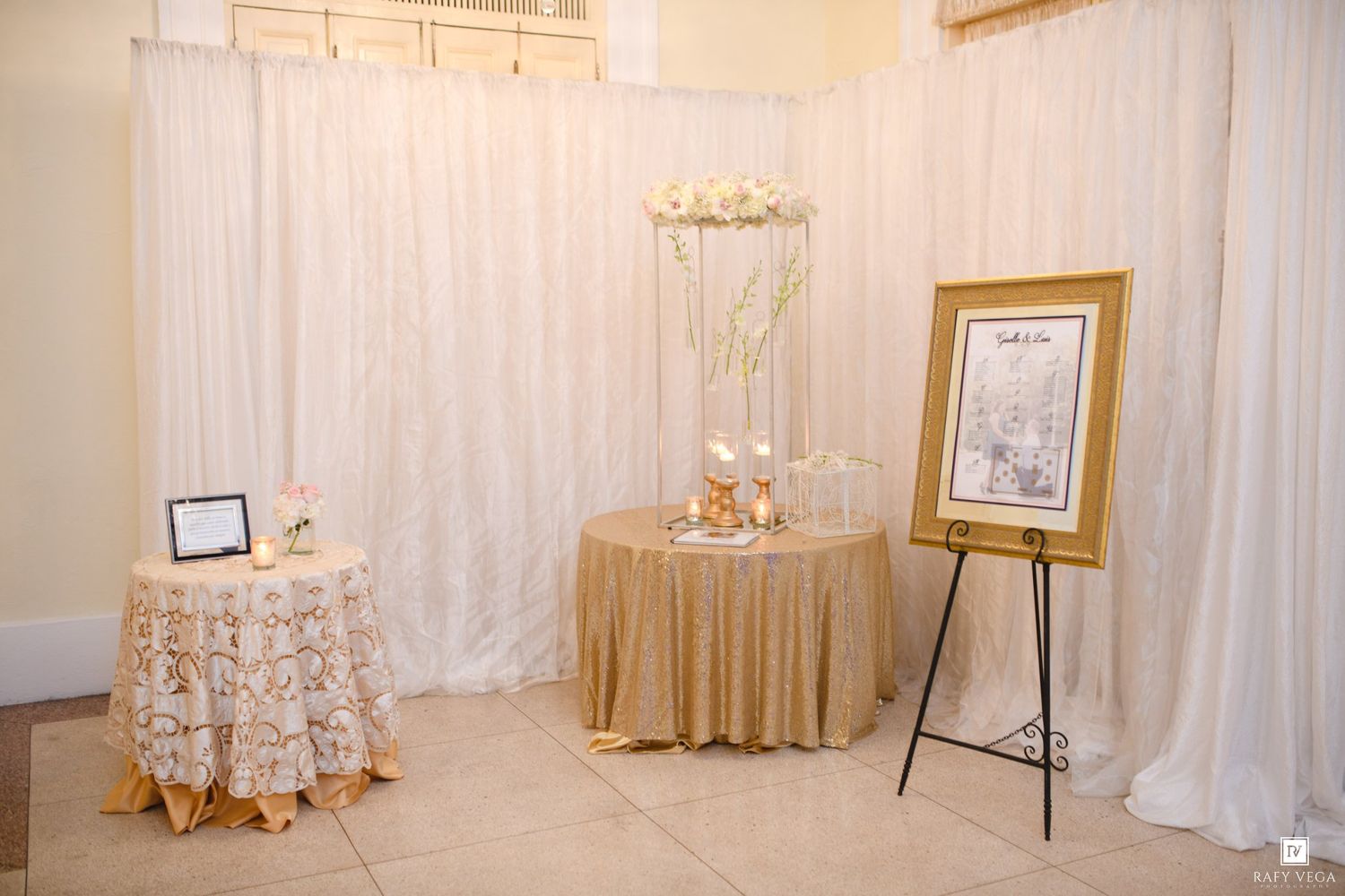 Elegant wedding reception entrance with gold sequin tablecloth, floral centerpiece, and framed seating chart on easel.