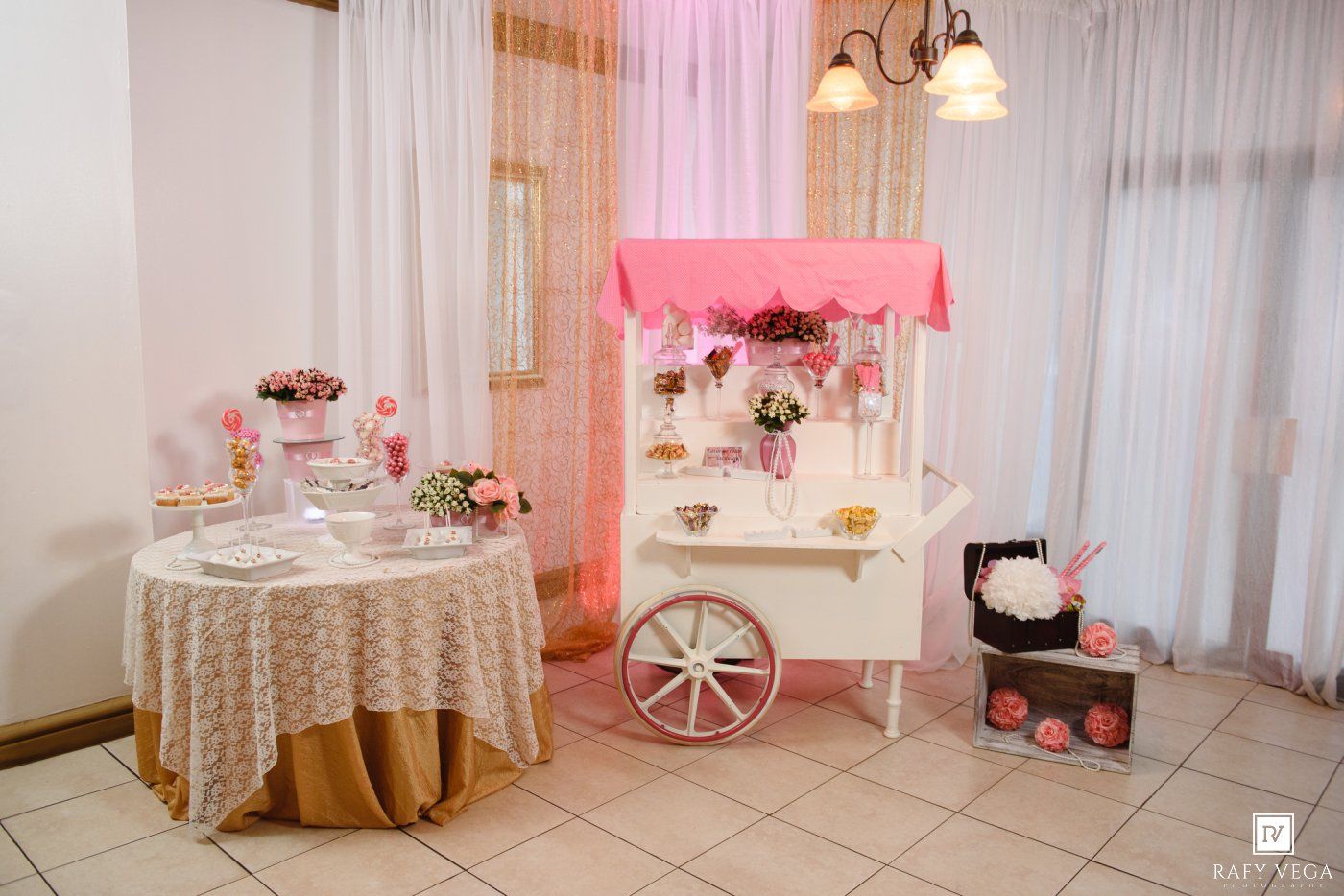 Charming pink and white candy cart display with floral decorations at an elegant wedding or quinceañera reception venue.