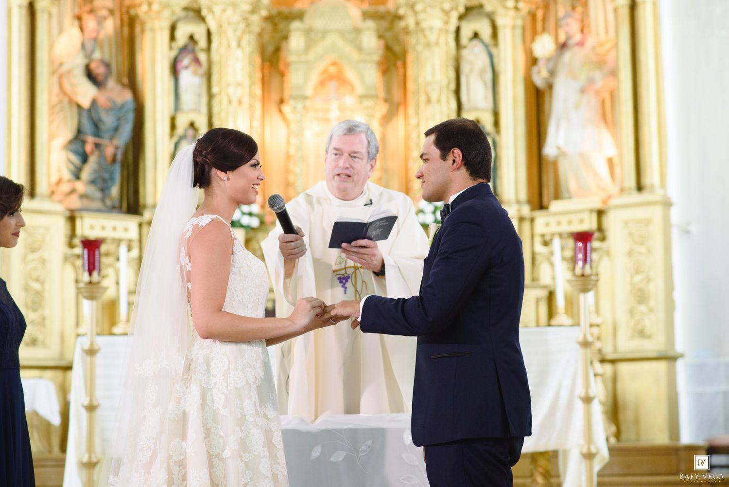 Bride and groom exchange vows at church altar with officiant during elegant wedding ceremony.
