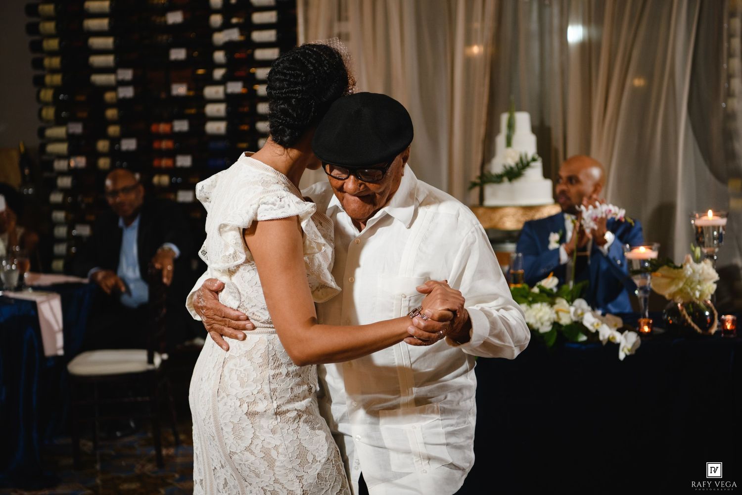 Two women share an emotional first dance at an elegant wedding reception with candlelit decor.