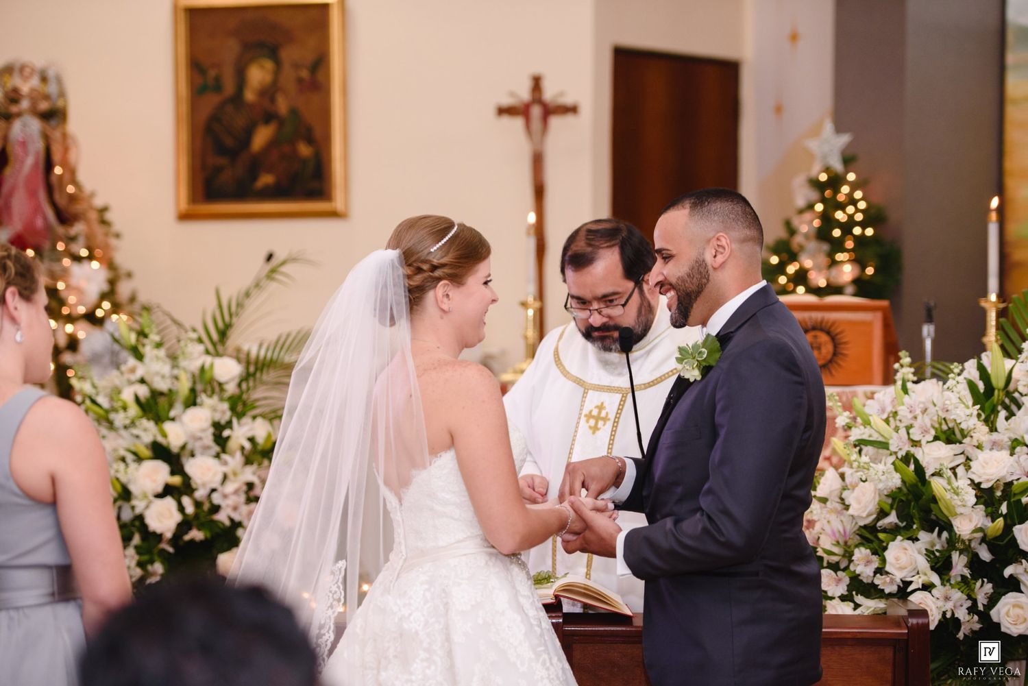 Bride and groom exchange vows at church altar with priest officiating.