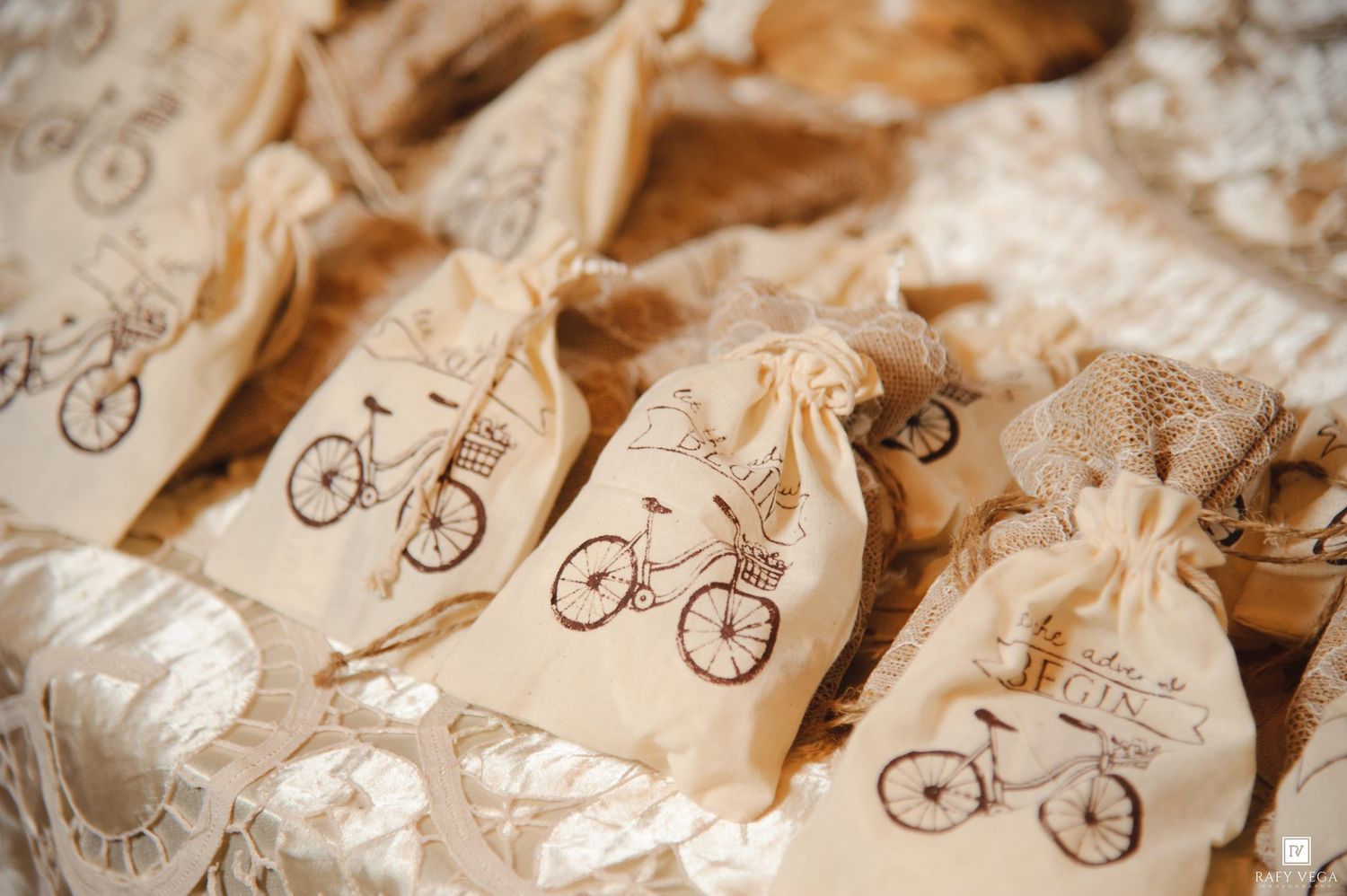 Rustic burlap favor bags stamped with vintage bicycle design arranged on lace fabric for a wedding reception.