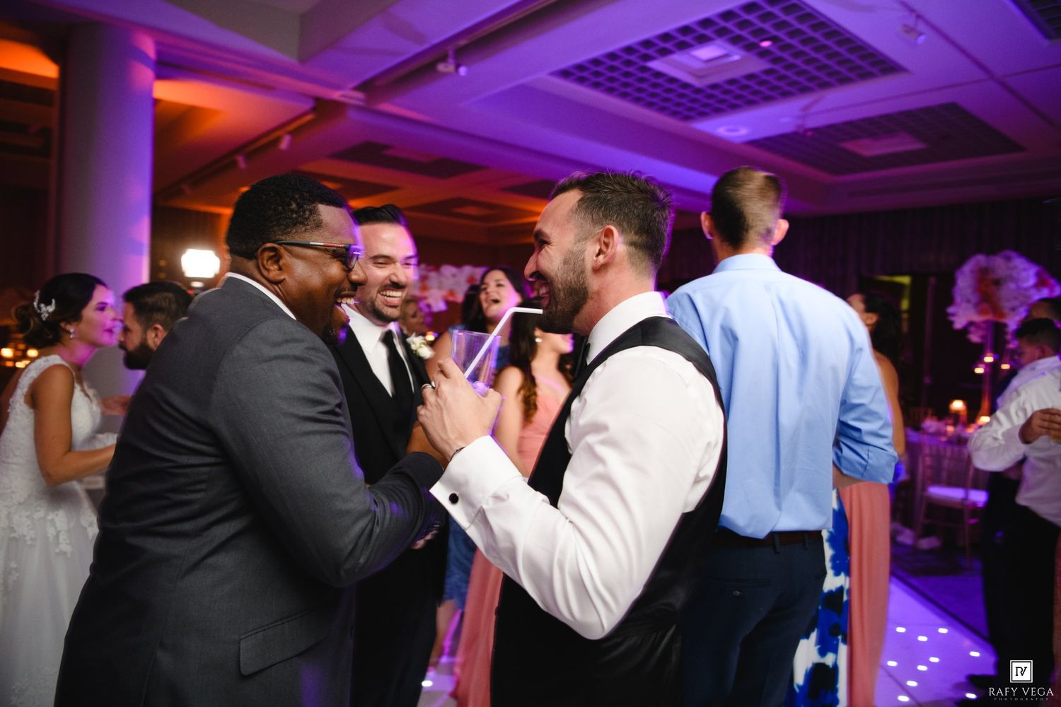 Groom sharing joyful moment with guest on wedding reception dance floor.
