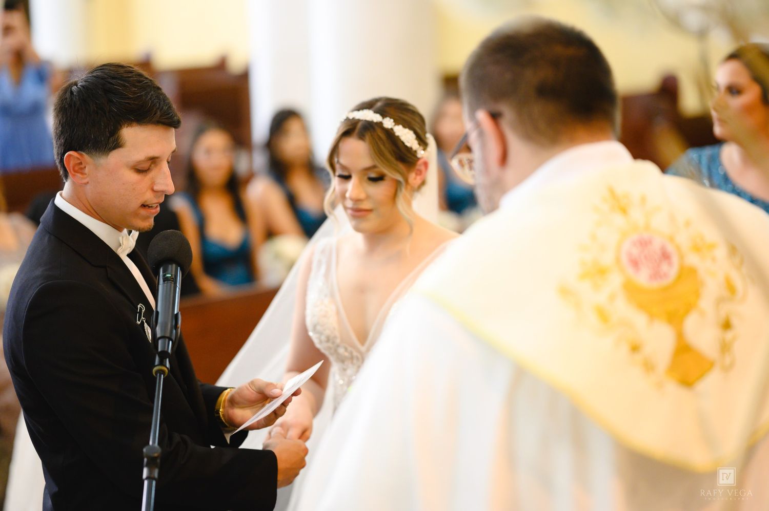 Bride and groom exchanging vows at a church wedding ceremony with a priest officiating.