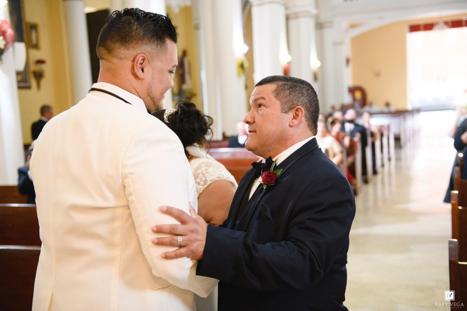 Two men sharing an emotional moment at the altar during a church wedding ceremony.