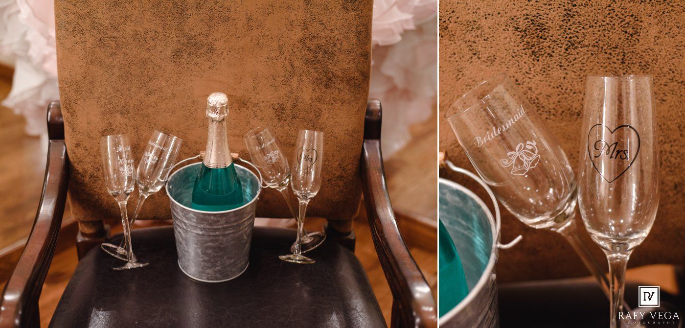 Elegant wedding champagne flutes with monogram engraving beside a silver ice bucket on a wooden chair.