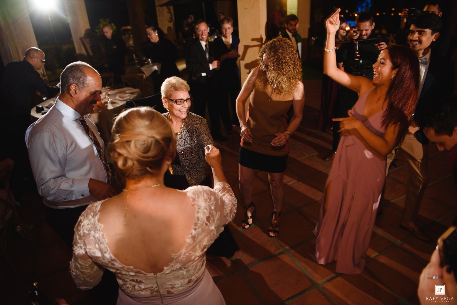 Guests dancing and celebrating at an elegant wedding reception in a warmly lit venue.
