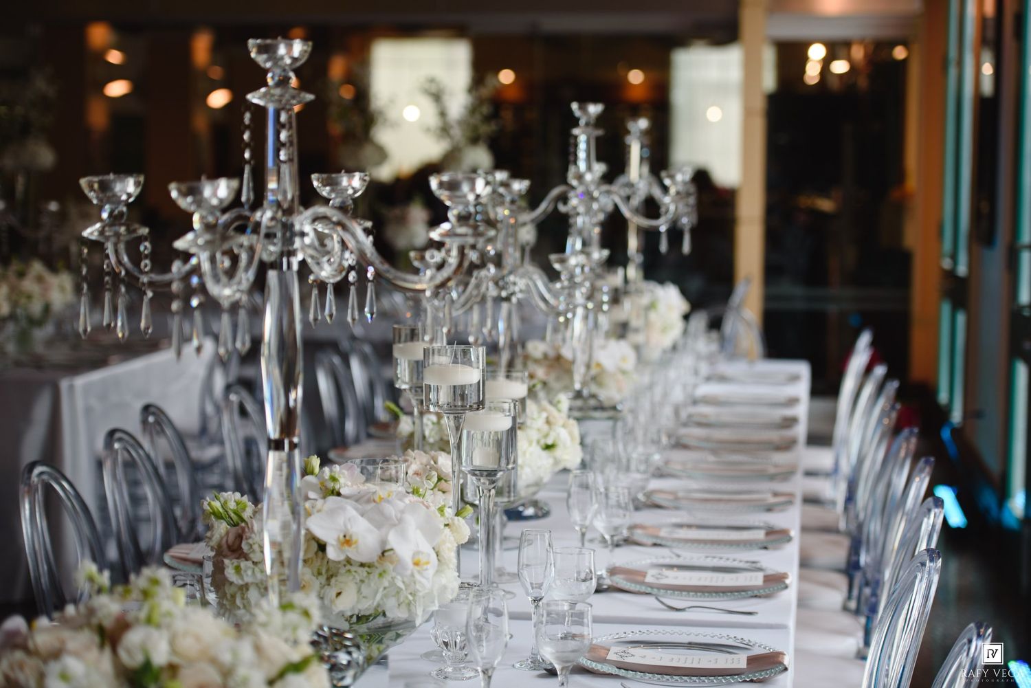 Elegant wedding reception table with crystal candelabras, white floral centerpieces, and fine dining settings in a luxurious venue.