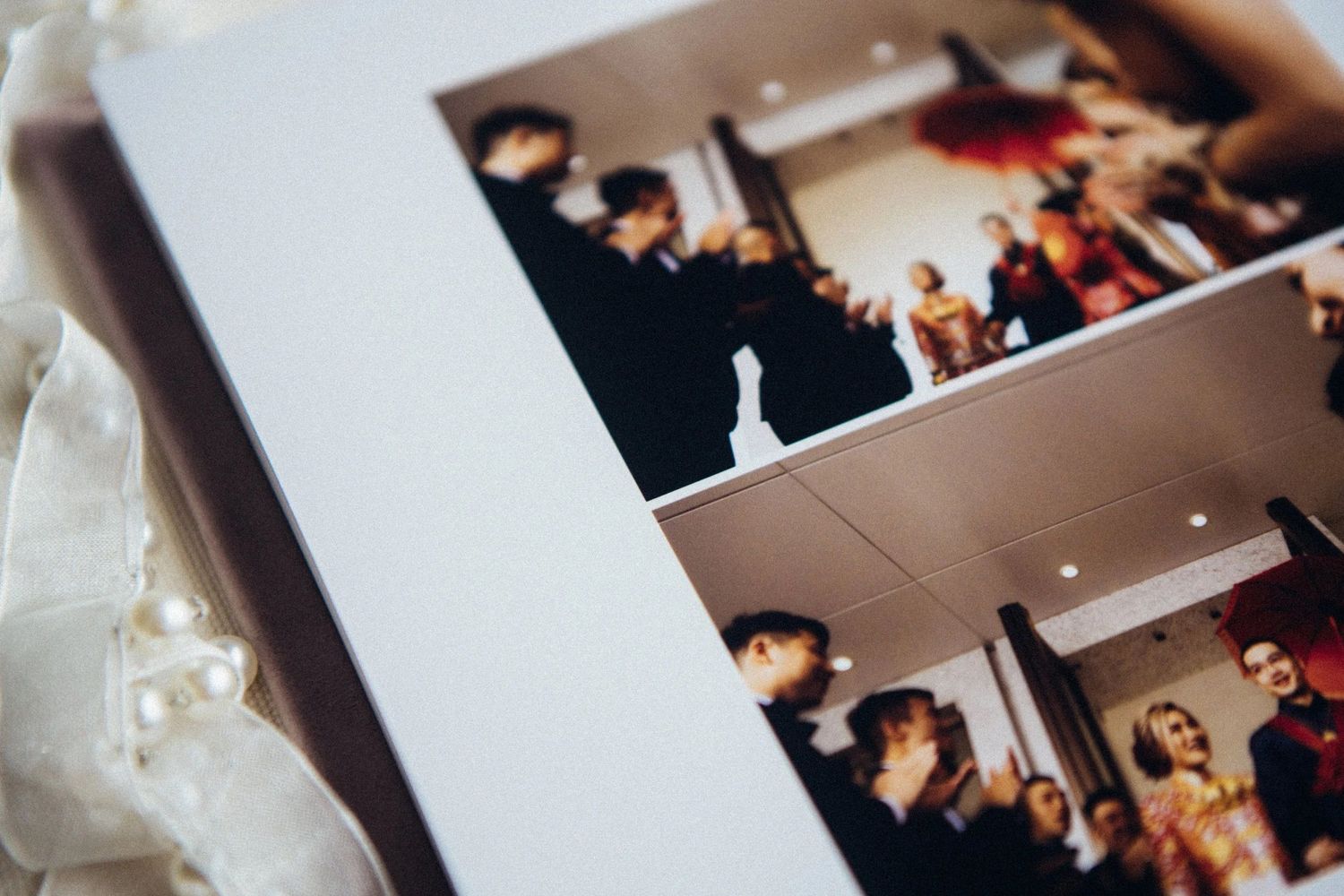 Close-up of a wedding photo album displaying elegant reception ceremony photos with guests in formal attire.