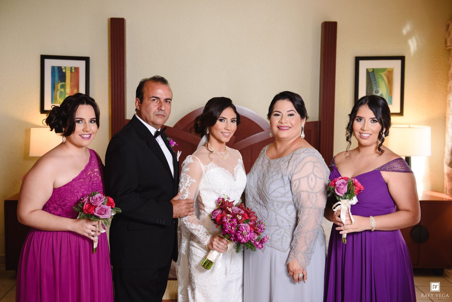 Wedding party portrait with bride, groom, bridesmaids in purple dresses and mother in silver gown.