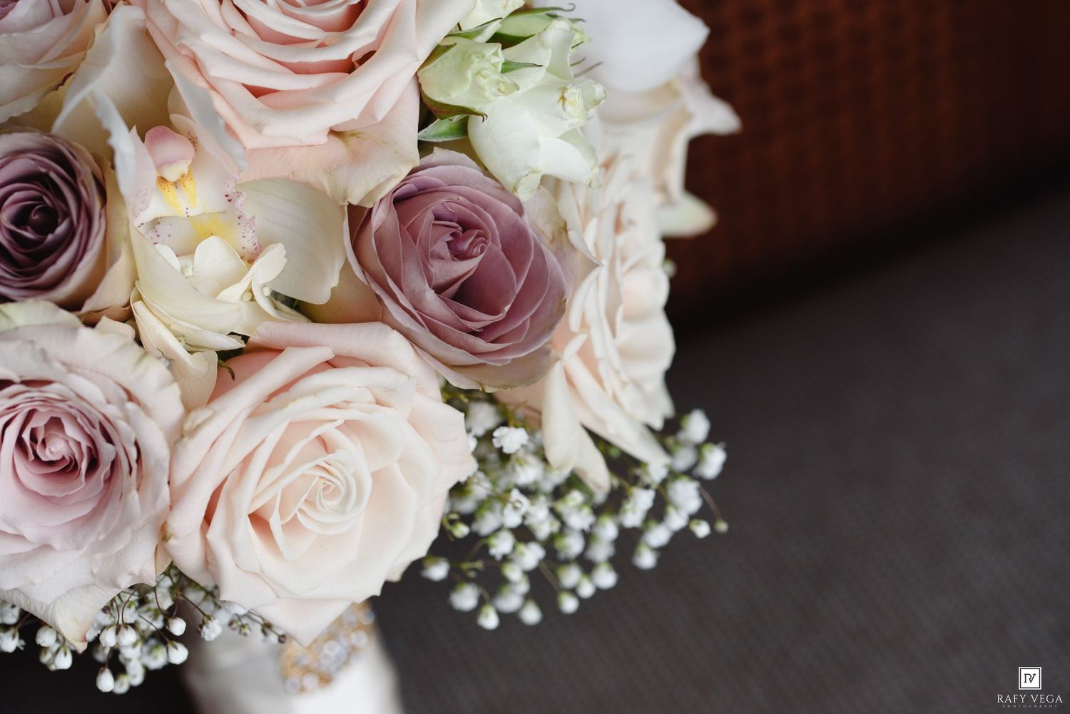 Close-up of an elegant bridal bouquet featuring blush pink and mauve roses with white baby's breath accents.