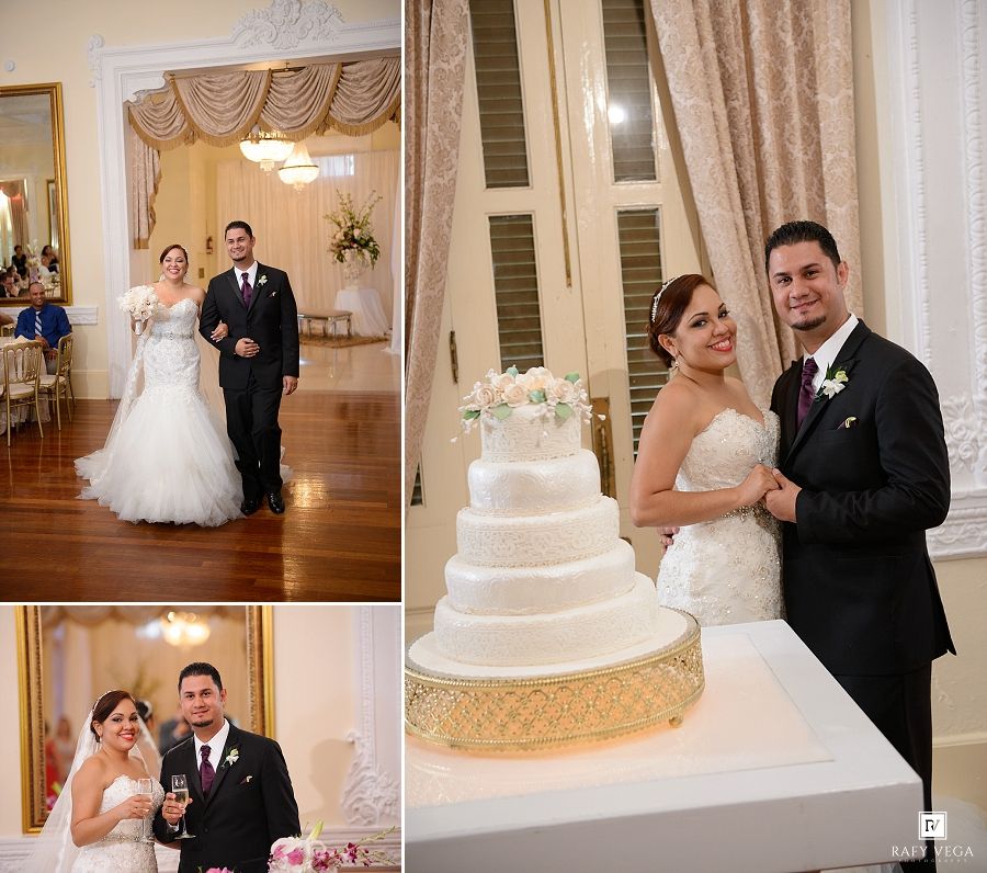 Bride and groom pose together at elegant wedding reception venue beside a white four-tier wedding cake on a gold stand.